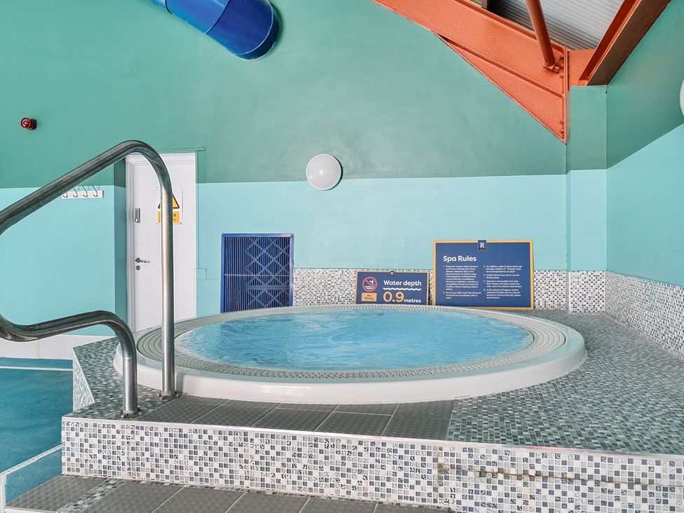 An indoor spa pool with tiled steps and metal handrail and spa rules on the wall at Seaside Serenity - Hayling Island in Hayling Island Holiday Park