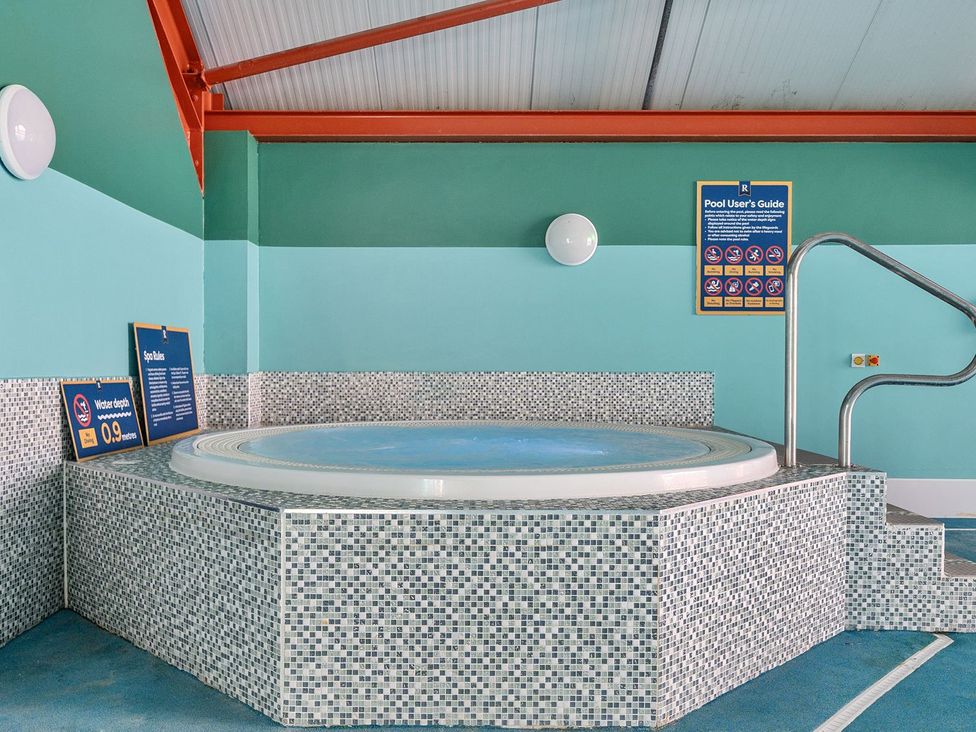 An indoor hot tub with tiled sides and safety railings at Seaside Serenity - Hayling Island Holiday Park