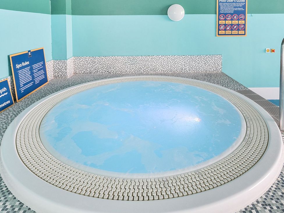 An indoor circular spa pool with blue water and tiled walls with spa rules and pool users guide signs at Seaside Serenity - Hayling Island in Hayling Island Holiday Park