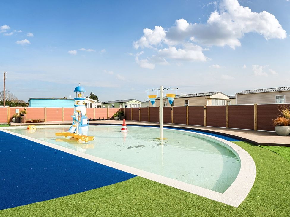 A small outdoor children's pool with water play features near caravans at Seaside Serenity Hayling Island Holiday Park