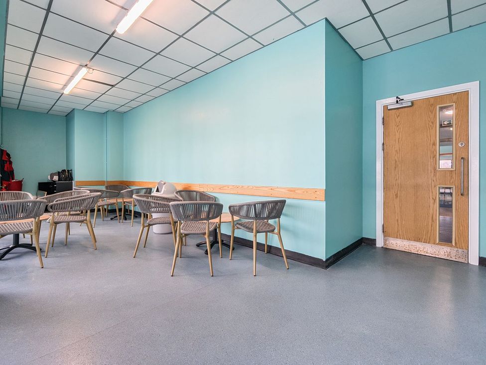An indoor seating area with multiple tables and chairs and a wooden door with windows at Seaside Serenity - Hayling Island in Hayling Island Holiday Park