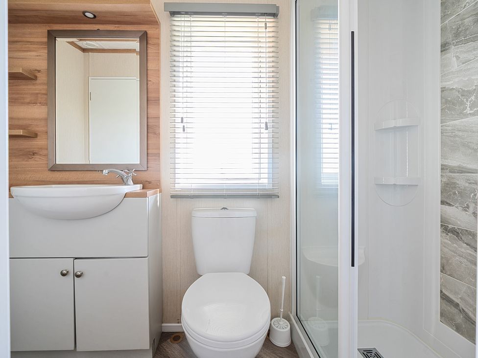 A bathroom with a sink and cabinet mirror toilet window with blinds and a shower cubicle at Seaside Serenity - Hayling Island Hayling Island Holiday Park