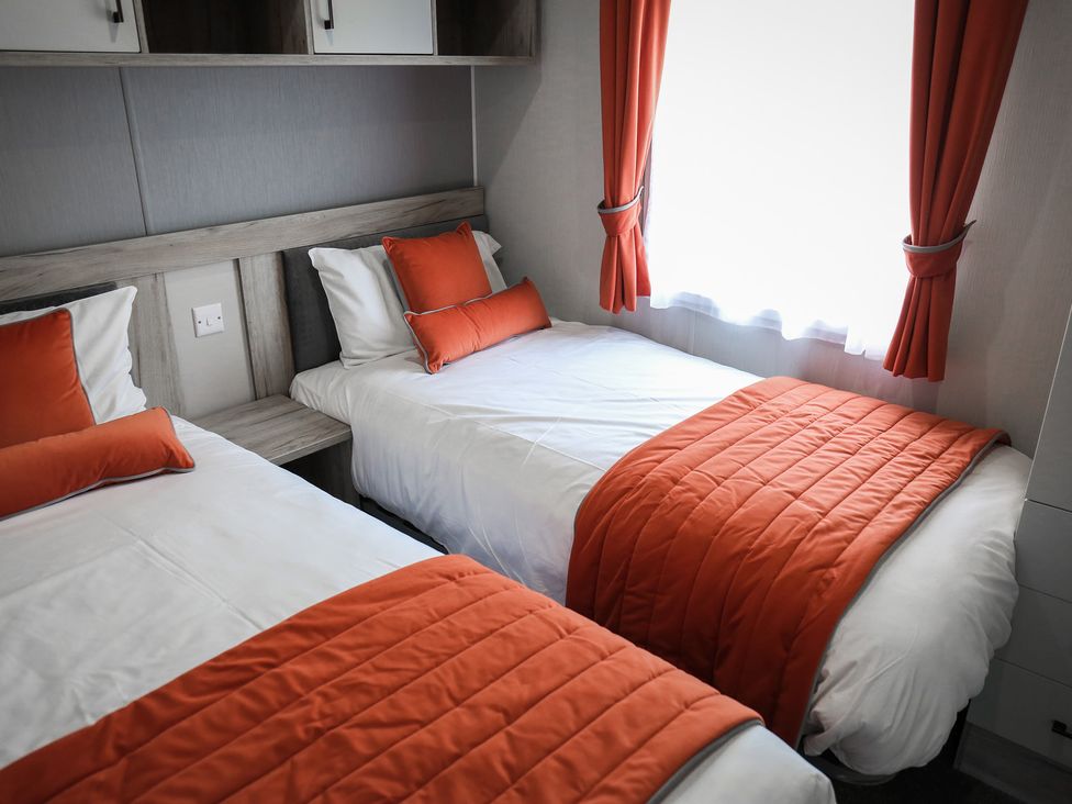A bedroom with two beds and orange accents at Sandy Shores - Hayling Island