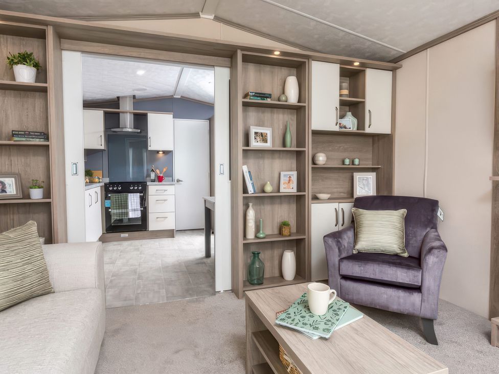 A living room with a bookshelf and armchair at Sandy Shores - Hayling Island