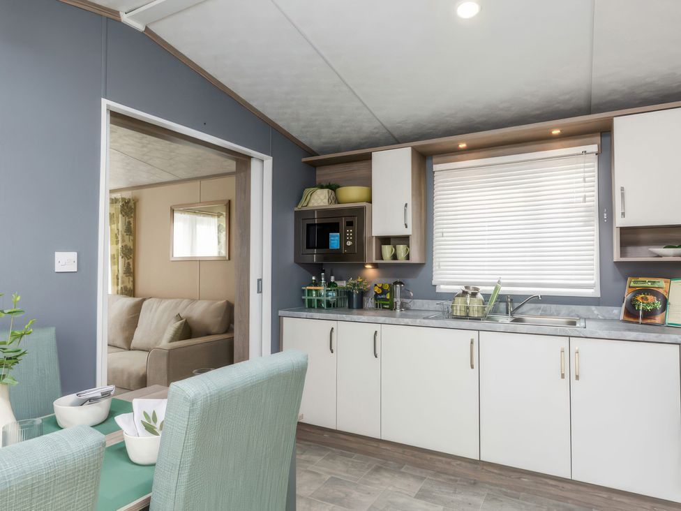 A kitchen with cabinets and appliances at Sandy Shores - Hayling Island