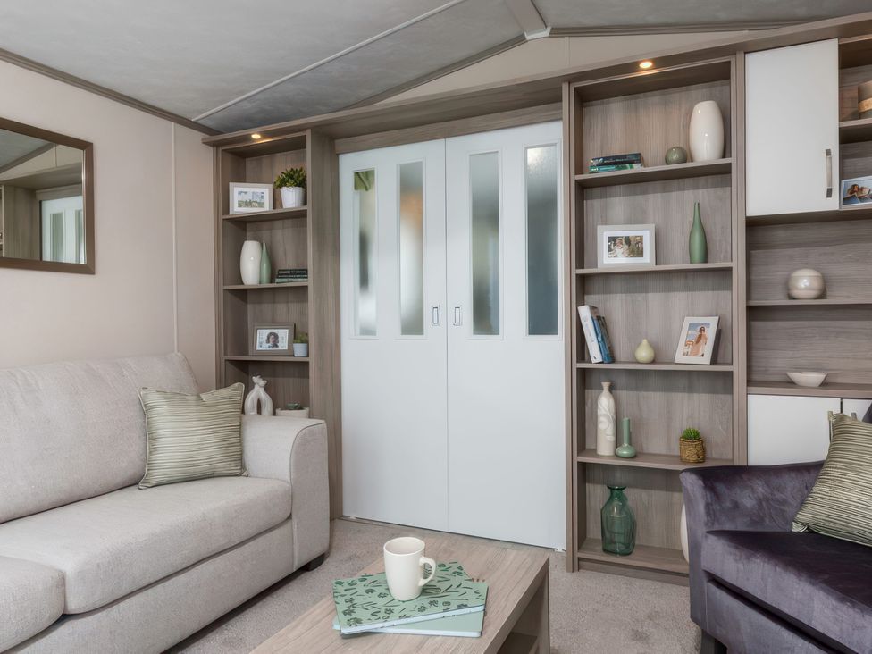 A living room with a sofa and bookshelf at Sandy Shores - Hayling Island
