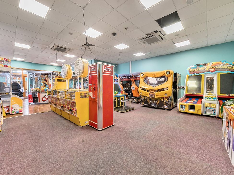 An indoor arcade room with various game machines including claw machines racing simulators and a ticket station at Island Breeze - Hayling Island in Hayling Island Holiday Park