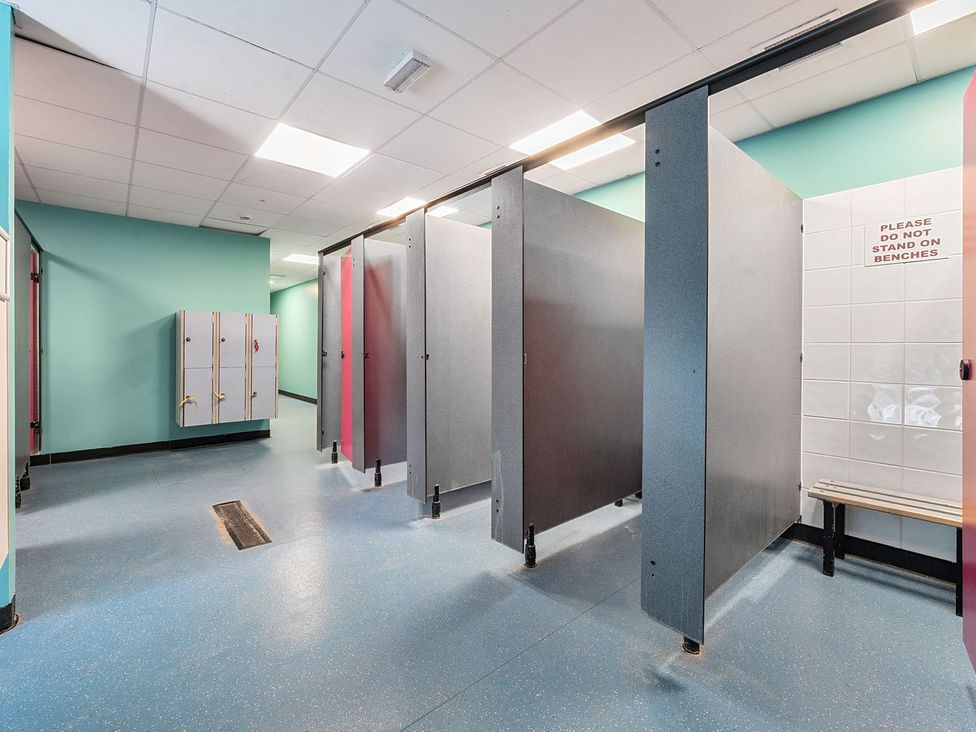 A changing room with lockers shower cubicles and a bench at Island Breeze - Hayling Island in Hayling Island Holiday Park