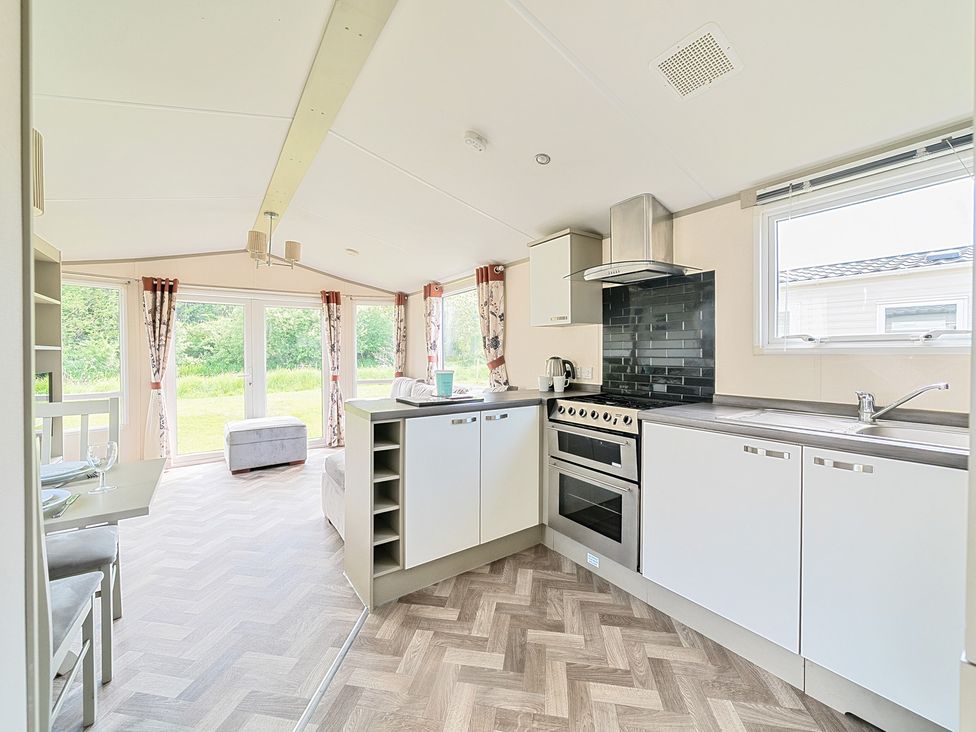 A kitchen with stove and sink next to a dining area and living room at Island Breeze - Hayling Island in Hayling Island Holiday Park