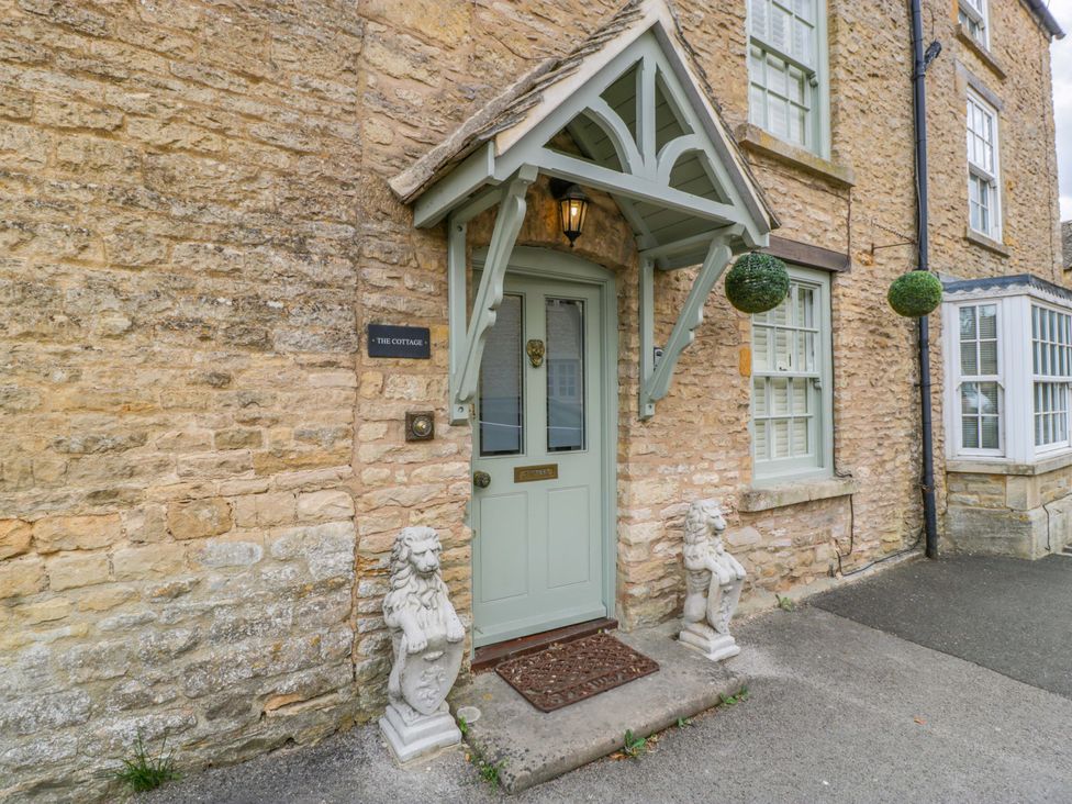 An entrance with a green door and lion statues at The Cottage in Stow-On-The-Wold