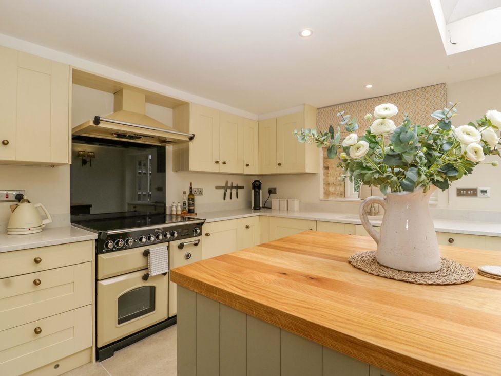 A kitchen with an oven, sink, and vase with flowers at The Cottage Stow-On-The-Wold
