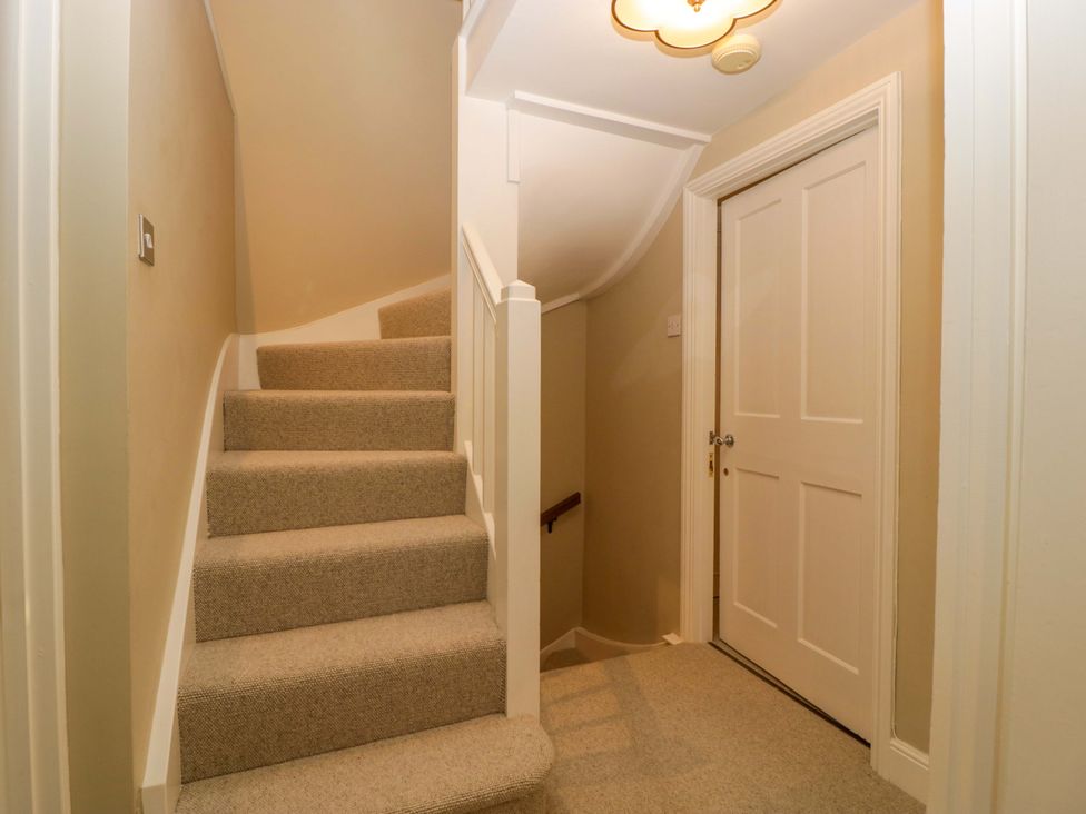 A staircase leading to a door in a hallway at The Cottage Stow-On-The-Wold