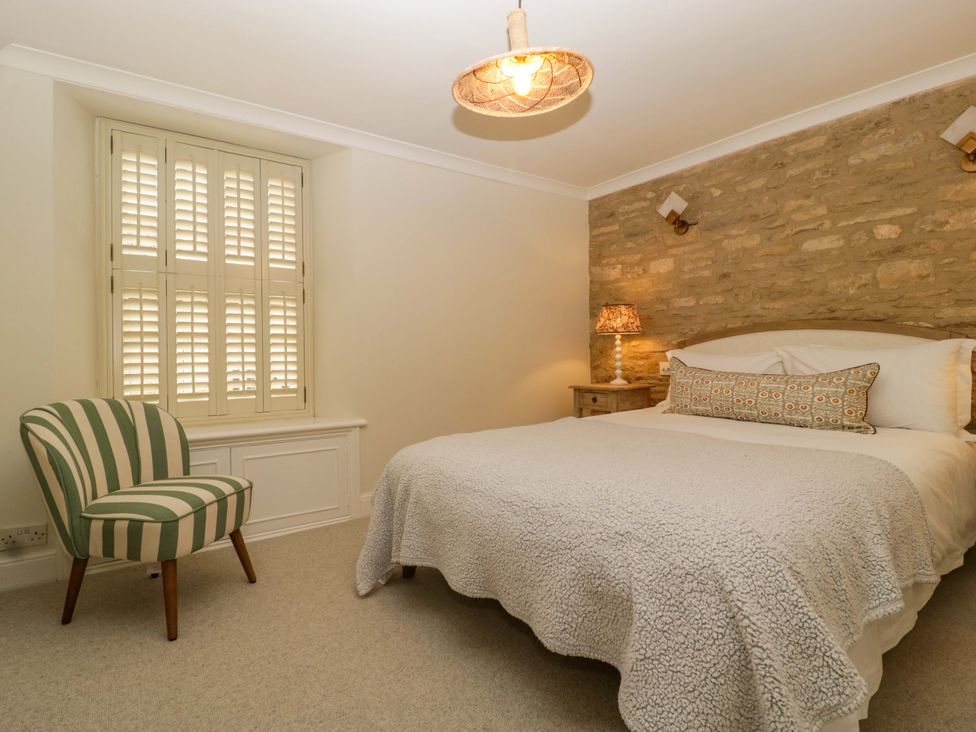 A bedroom with a bed, side table, and chair at The Cottage in Stow-On-The-Wold