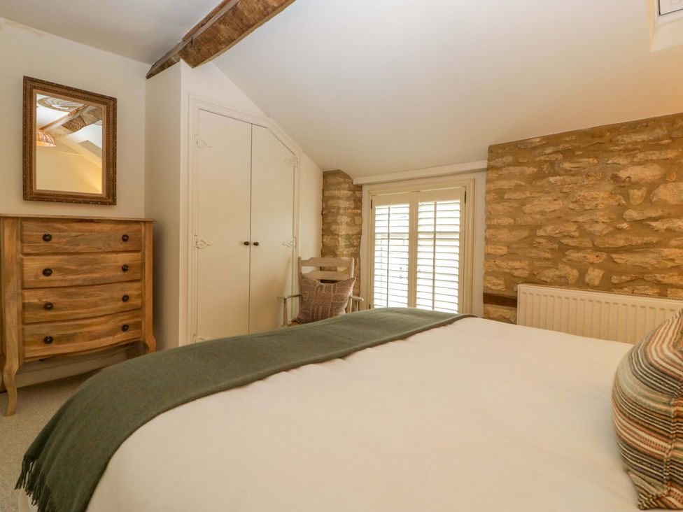 A bedroom with a bed and wooden furniture at The Cottage in Stow-On-The-Wold