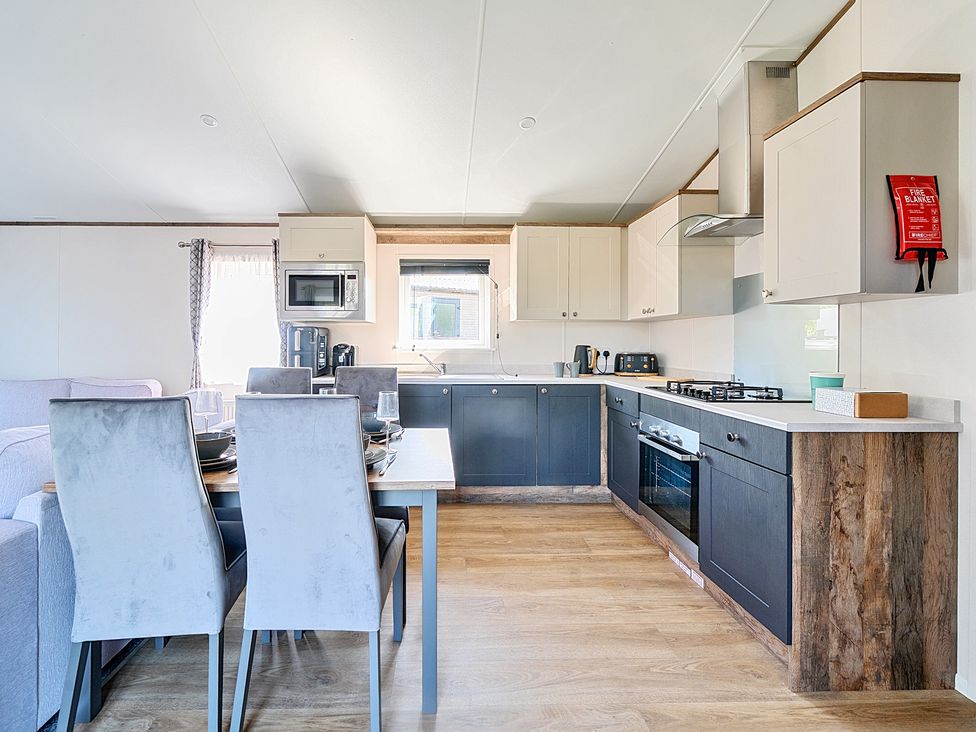 A kitchen and dining area with chairs a table and appliances at Wave Whisperers - Hayling Island in Hayling Island Holiday Park