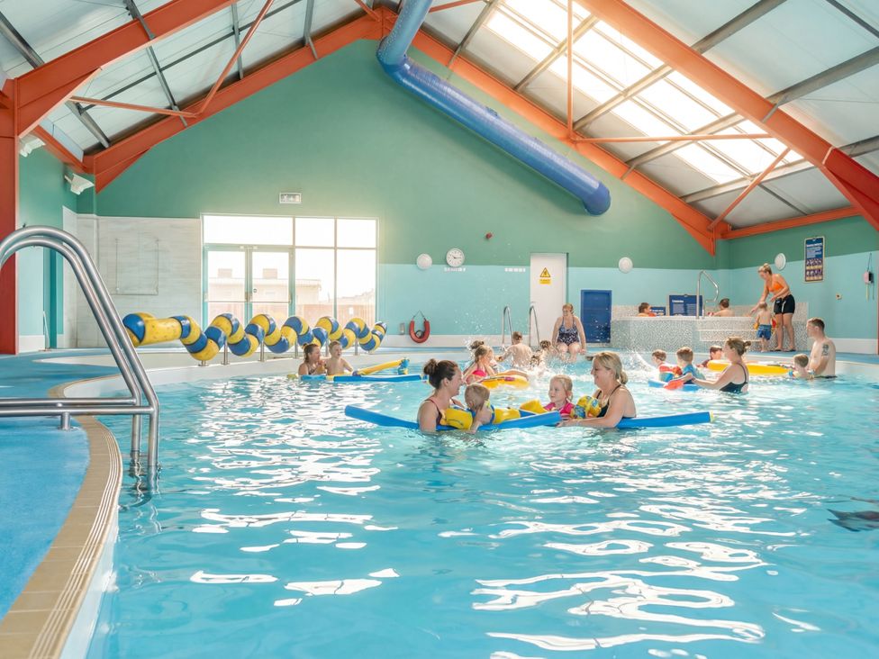 A swimming pool with children and adults participating in water activities at Golden Dune - Hayling Island