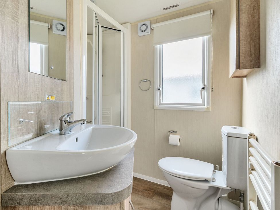 A bathroom with a sink countertop toilet shower and window at The Lookout - Hayling Island in Hayling Island Holiday Park