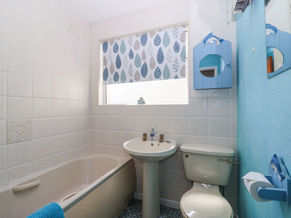 A bathroom with a bathtub sink toilet and a window with a leaf patterned blind at Ambermist in Churchstow