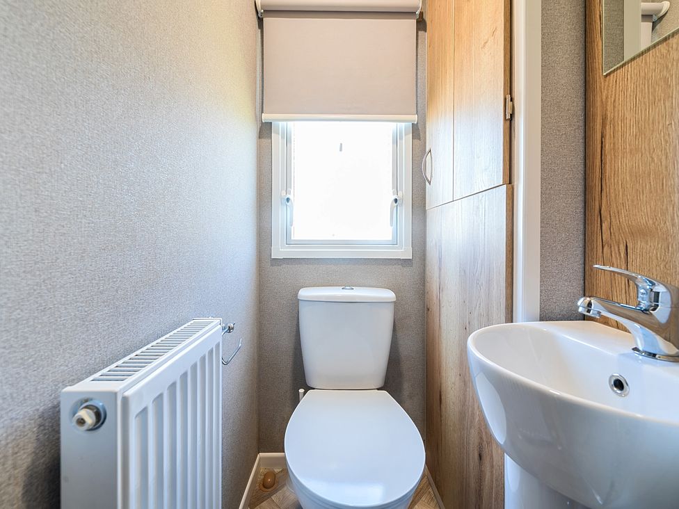 A small bathroom with a toilet radiator sink and window at Sunset Sands - Hayling Island Hayling Island Holiday Park