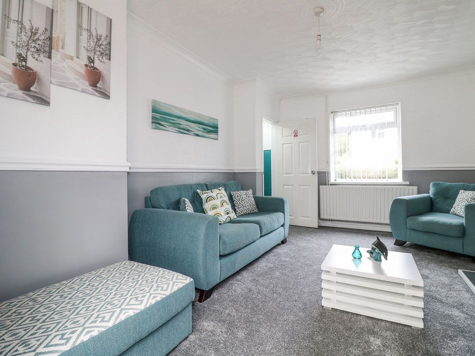 A living room with blue sofas a white coffee table and patterned ottoman at 46 Dalby Road in Antsey