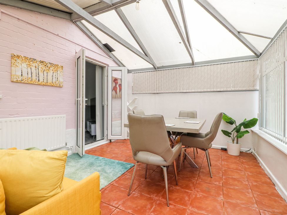 A conservatory with a dining table and chairs a yellow armchair and a potted plant at 46 Dalby Road in Antsey