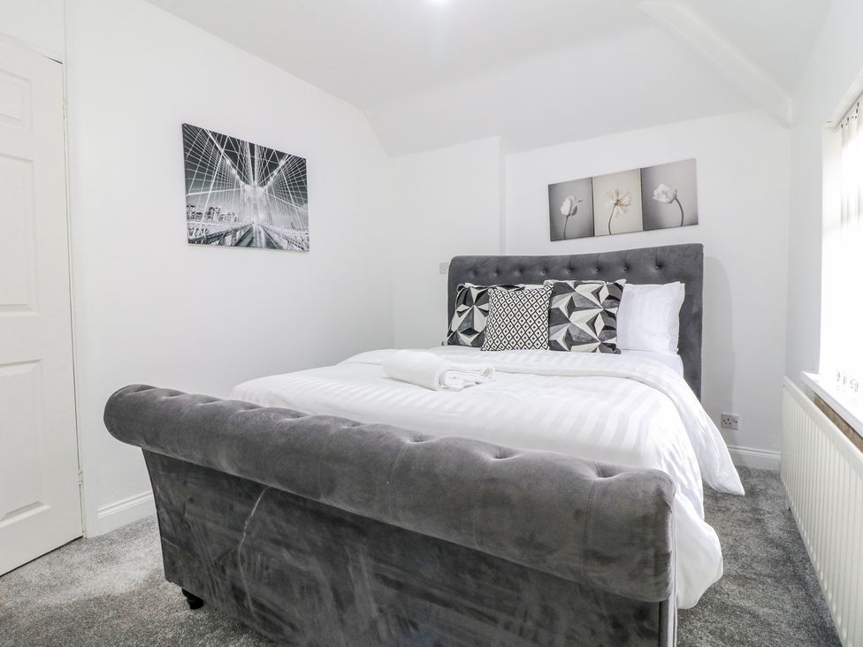 A bedroom with a gray upholstered bed and white linens and black and white wall art at 46 Dalby Road Antsey