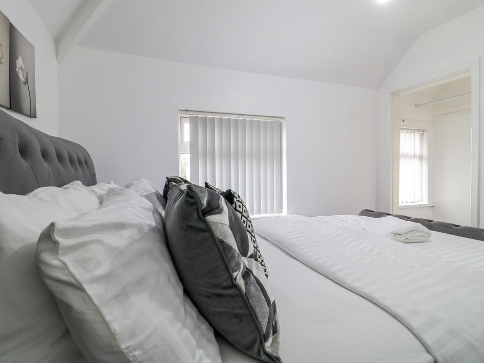 A bedroom with a bed with pillows and folded towel on the bed near windows with vertical blinds at 46 Dalby Road in Antsey