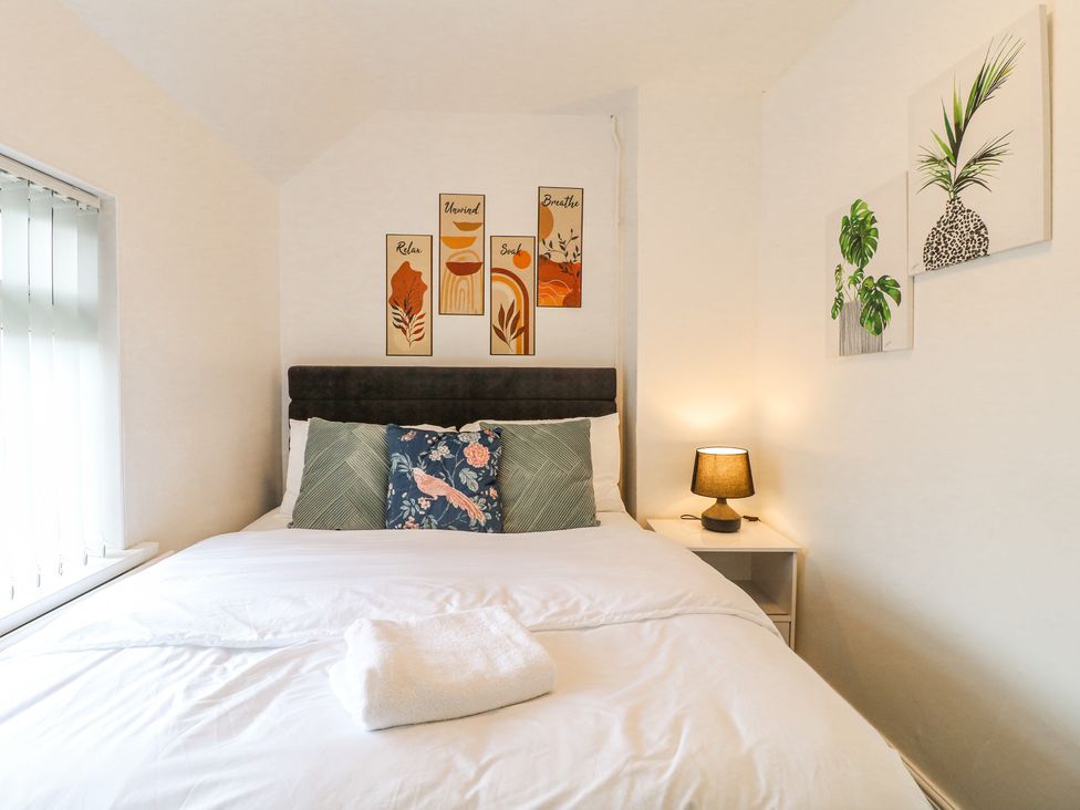 A bedroom with a double bed white bedding pillows and wall art at 46 Dalby Road Antsey