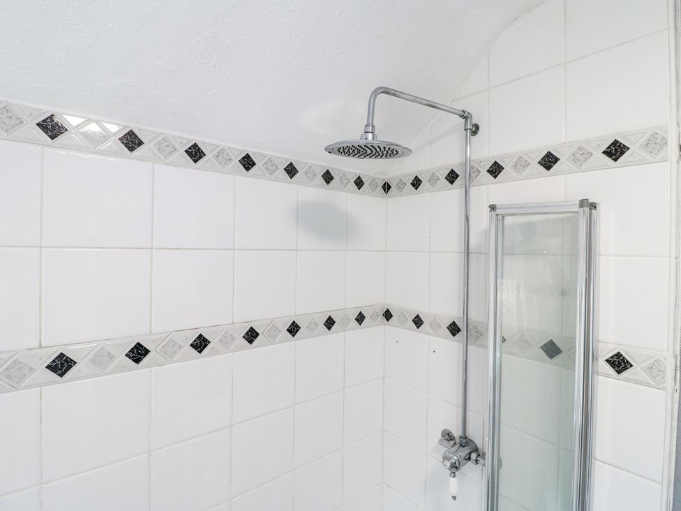 A shower area with a overhead shower and tiled walls with a black and white diamond pattern at 46 Dalby Road in Antsey