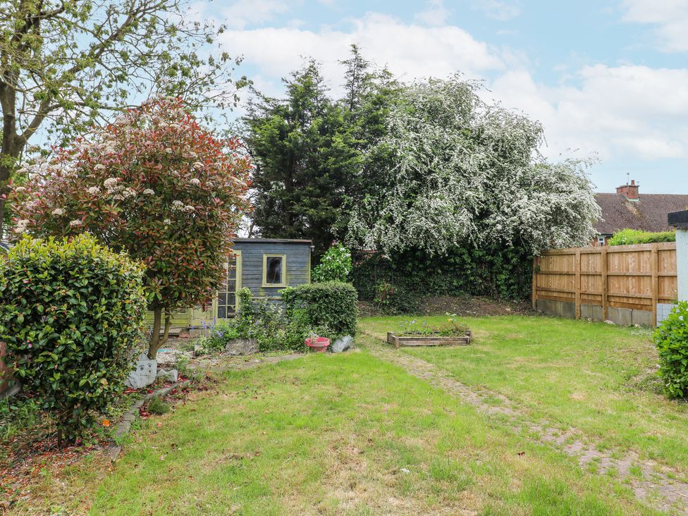 A backyard with grass lawn shrubs trees a wooden shed and a wooden fence at 46 Dalby Road in Antsey