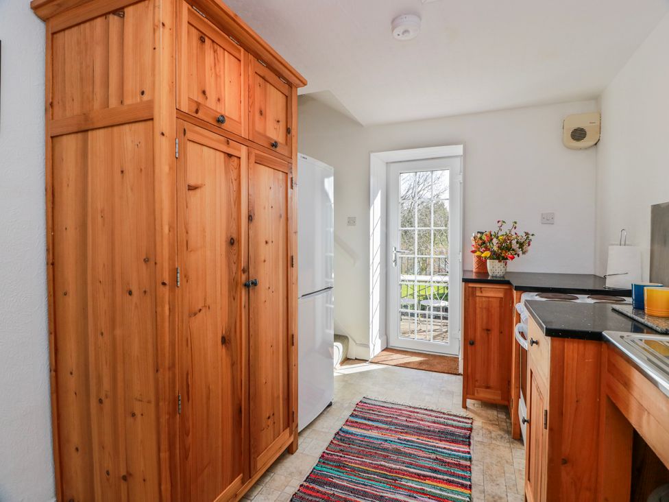 A kitchen with a cupboard and refrigerator at The Old Coach House Lockerbie