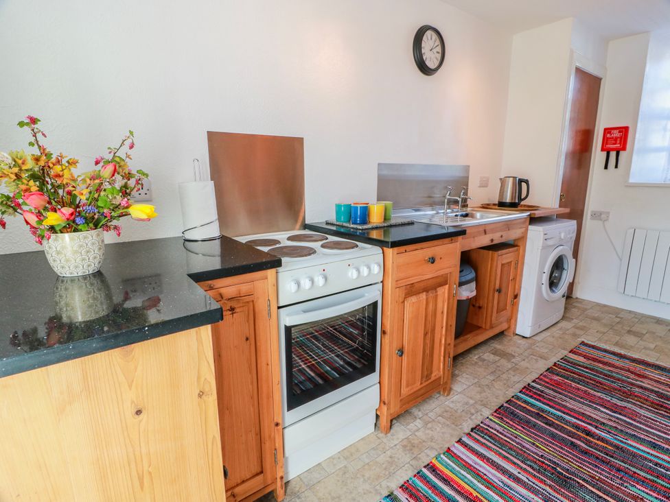 A kitchen with countertop, oven, sink and washing machine at The Old Coach House Lockerbie