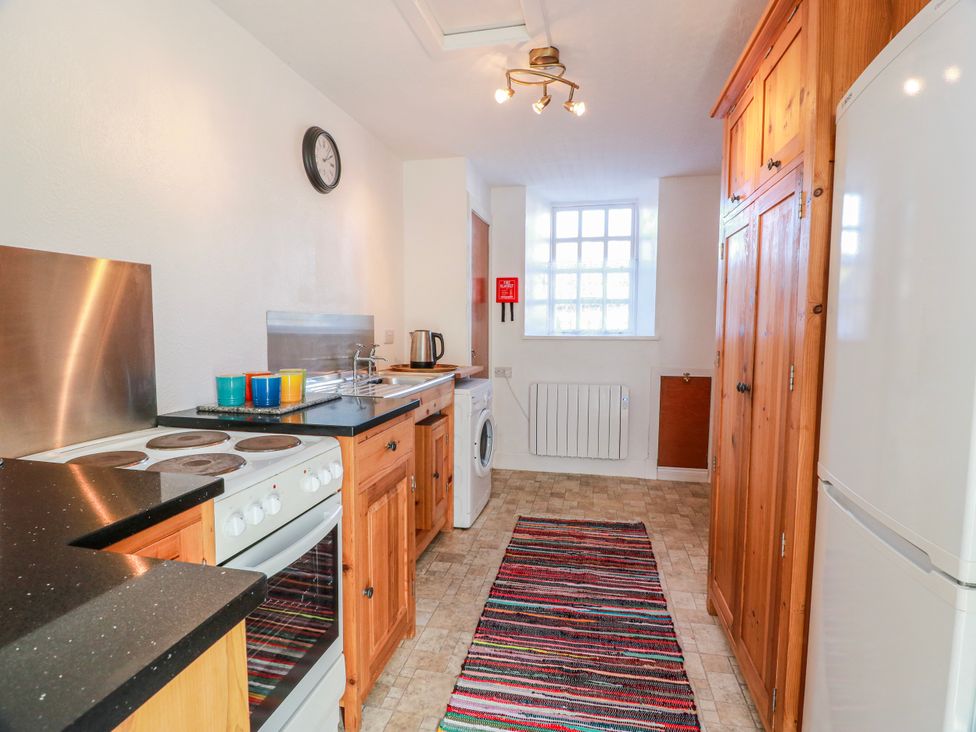 A kitchen with stove, sink and washing machine at The Old Coach House Lockerbie