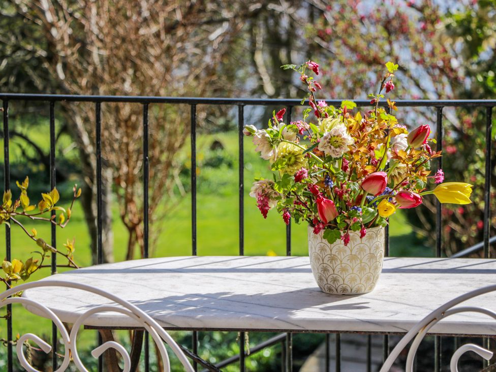 A table with flowers in a vase on a balcony at The Old Coach House Lockerbie