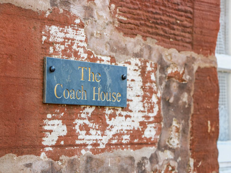 A sign on a brick wall indicating The Coach House in Lockerbie