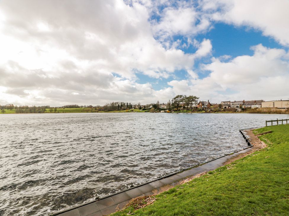 A view of a lake with grass and a path at The Old Coach House in Lockerbie