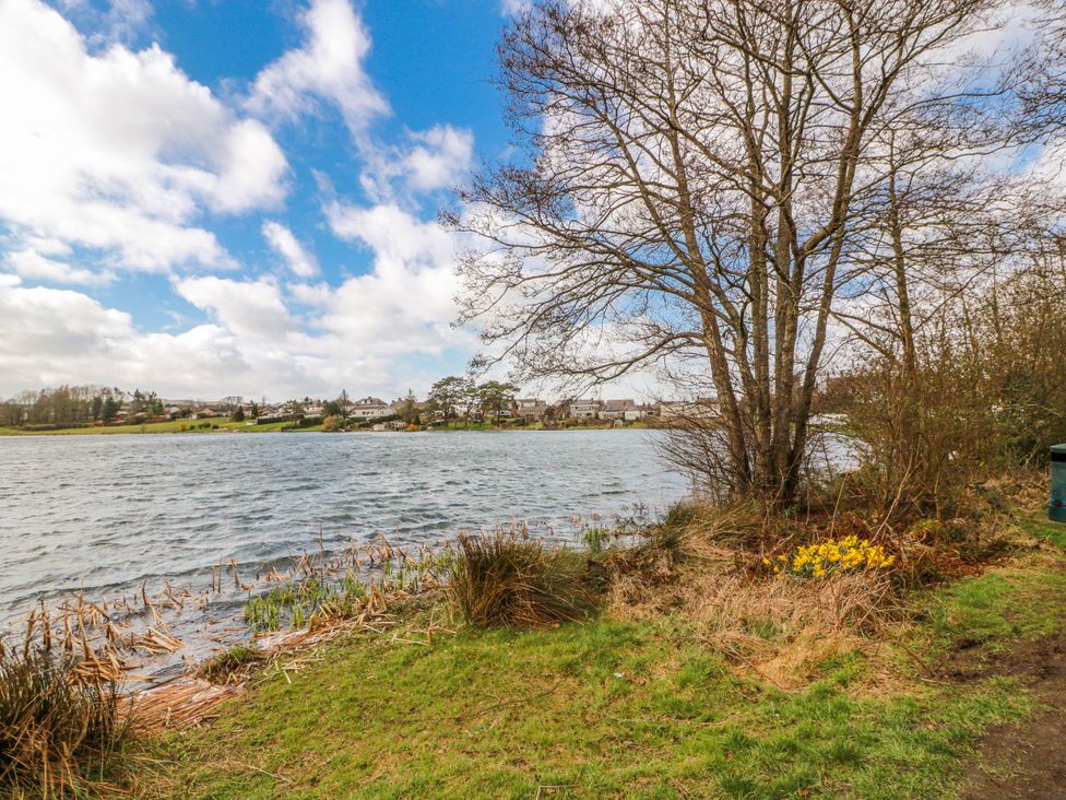 A view of a lake with trees and houses in the background at The Old Coach House Lockerbie