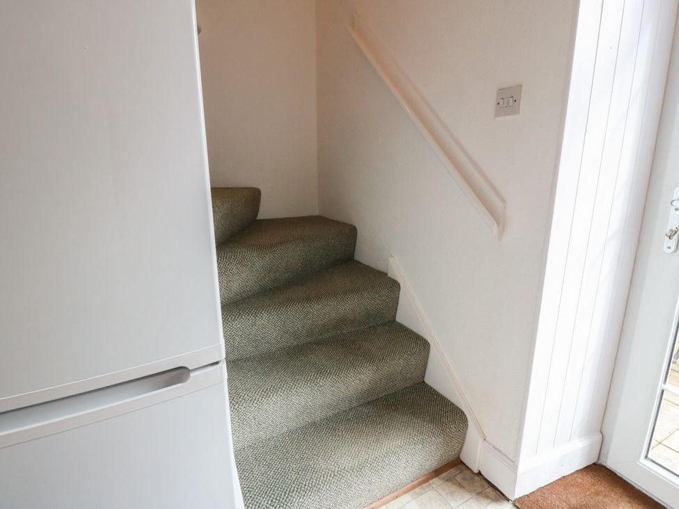 A staircase leading up with a fridge on the side at The Old Coach House in Lochmaben