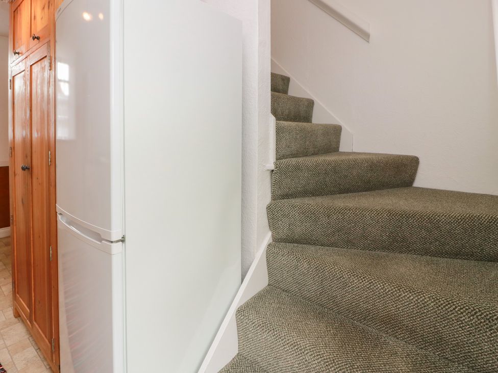 A staircase with a refrigerator and wooden cabinet at The Old Coach House Lochmaben