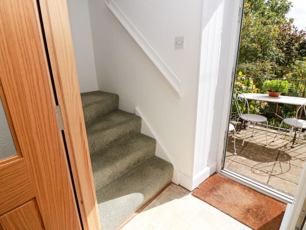 A hallway with stairs and an open door leading to an outdoor patio at The Old Coach House Lochmaben