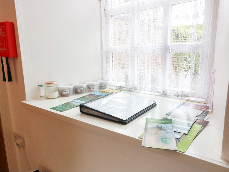 A shelf with candles, brochures, and a binder at The Old Coach House in Lochmaben