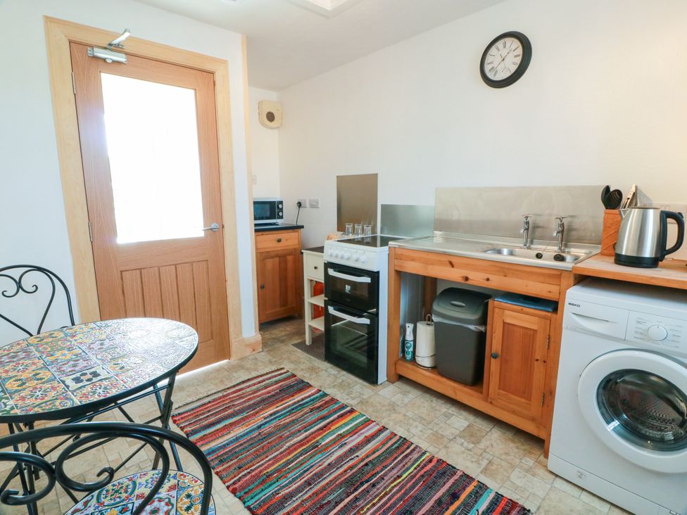 A kitchen with appliances and a table in The Old Coach House Lochmaben