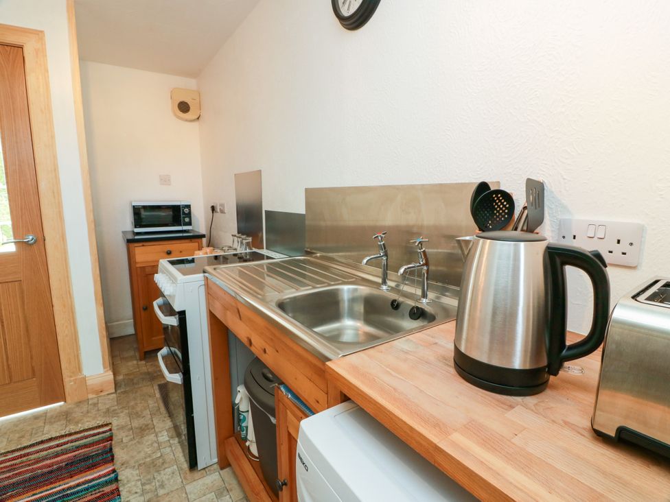 A kitchen with a sink, kettle, and microwave at The Old Coach House Lochmaben