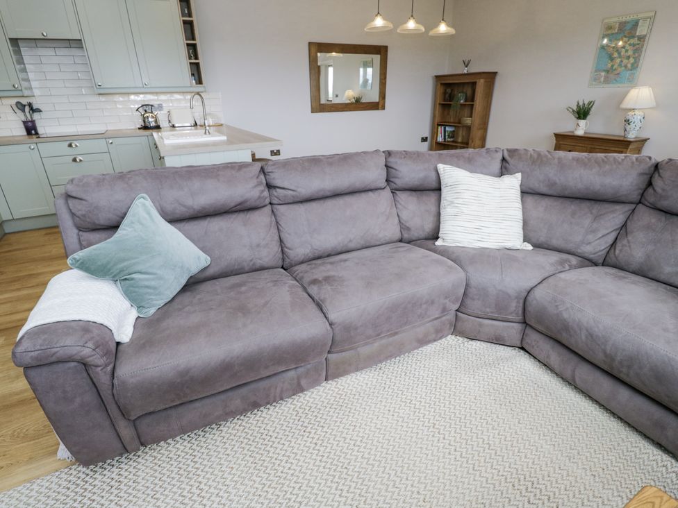 A living room with a sofa and kitchen area at Hayloft