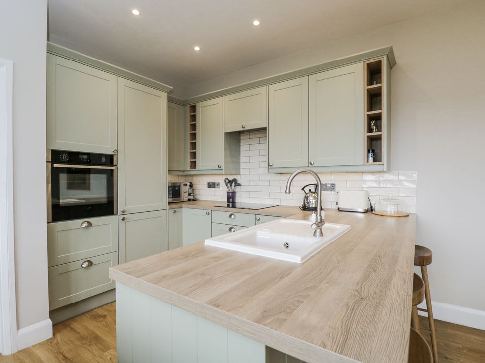 A kitchen with green cabinets and a wooden countertop at Hayloft in 