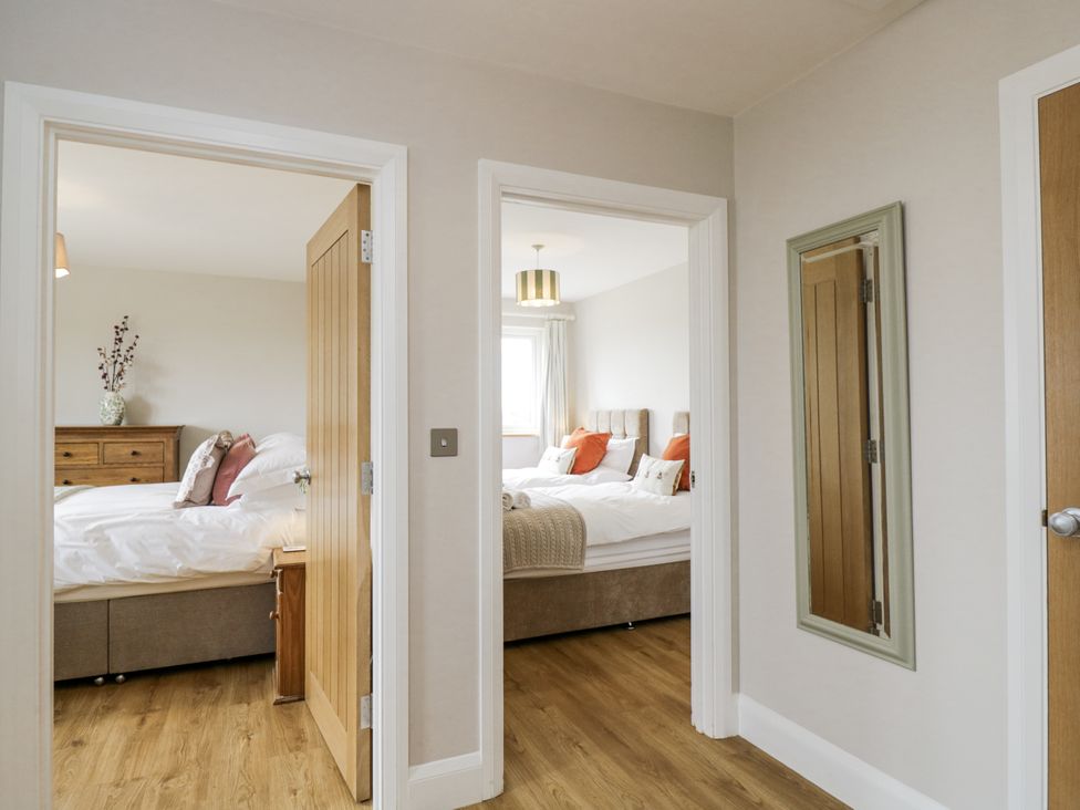 A view into two bedrooms with a mirror and dresser at Hayloft
