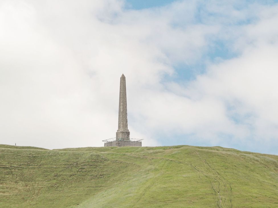 A monument on a grassy hill under a cloudy sky at Hayloft