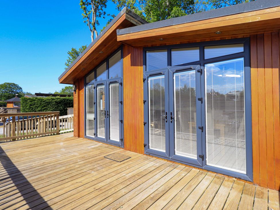 A wooden deck with glass doors and blinds on a wooden building at Kingfisher Lodge in Gargrave