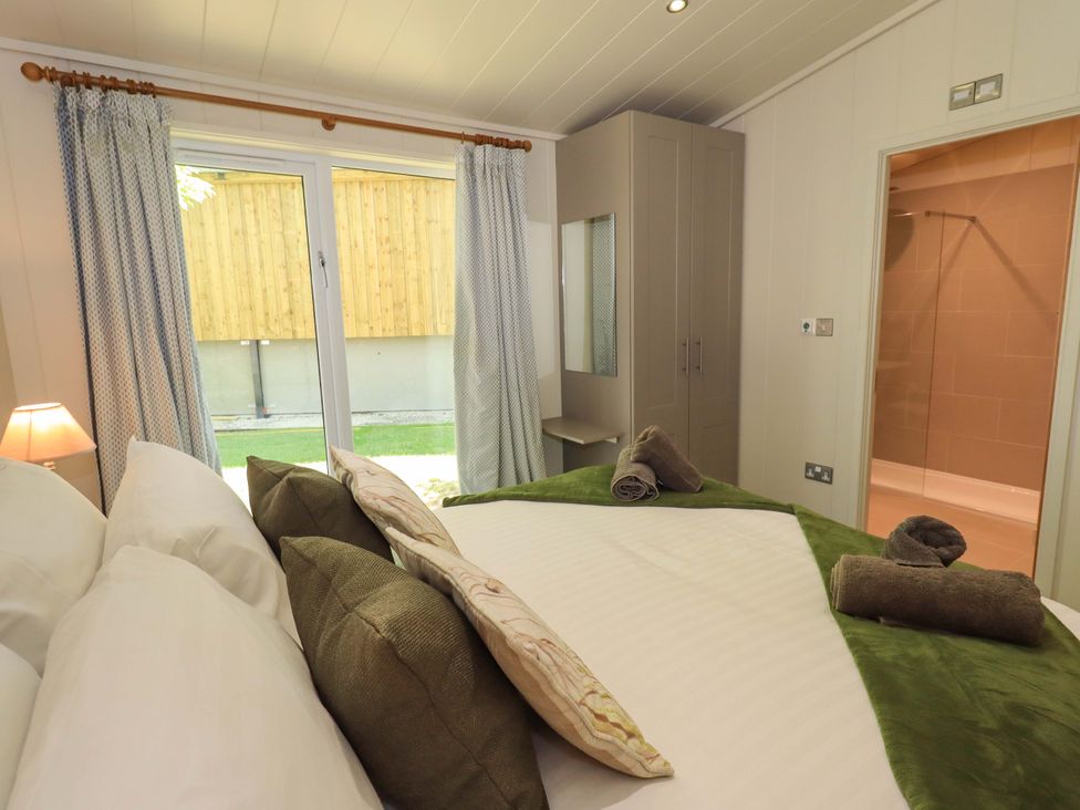 A bedroom with a bed towels wardrobe and a door leading to a bathroom at Kingfisher Lodge in Gargrave