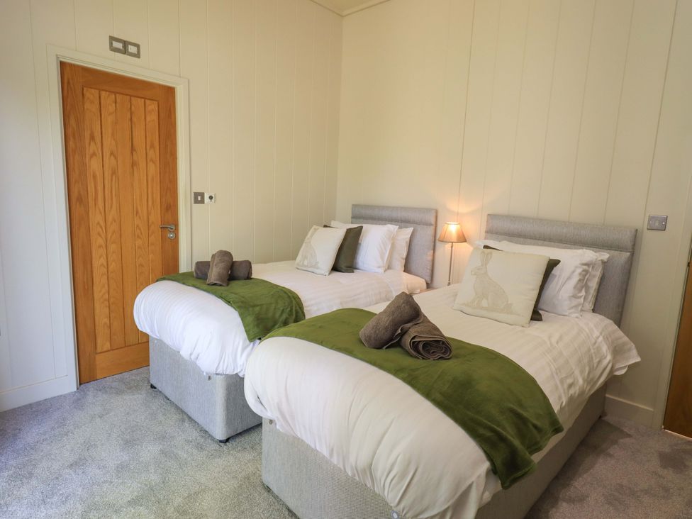A bedroom with two single beds towels and green throws on beds at Kingfisher Lodge in Gargrave